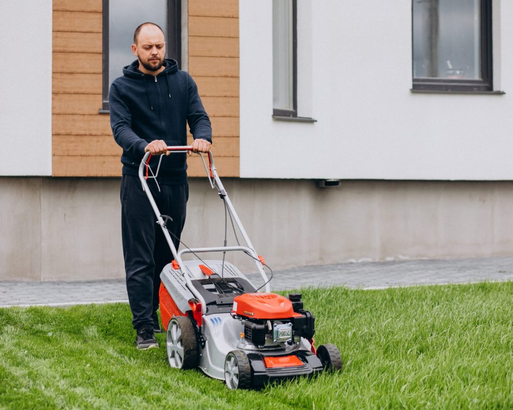 Man cutting grass with lawn mover in the back yard